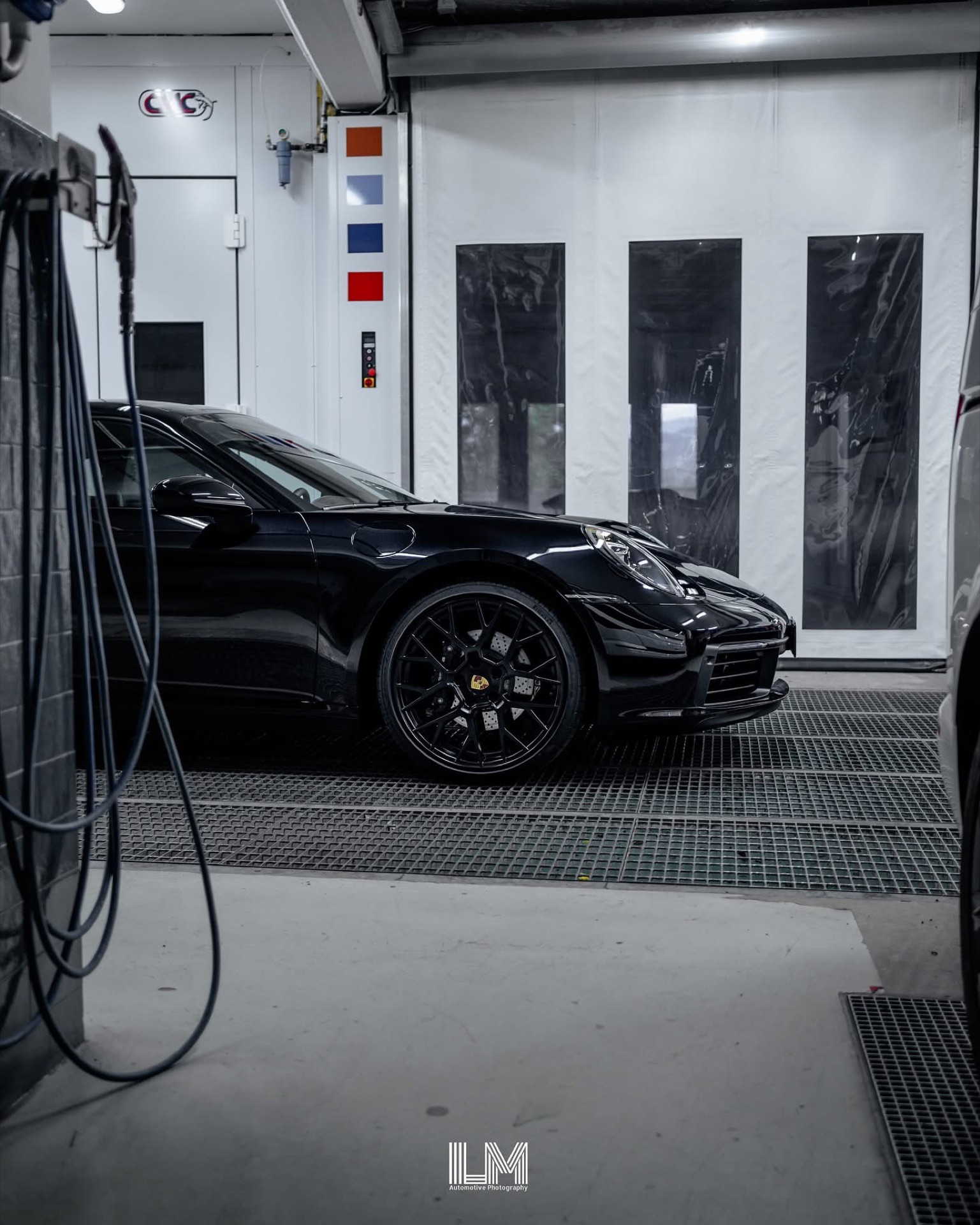 Porsche 911 992 nera nella cabina di verniciatura