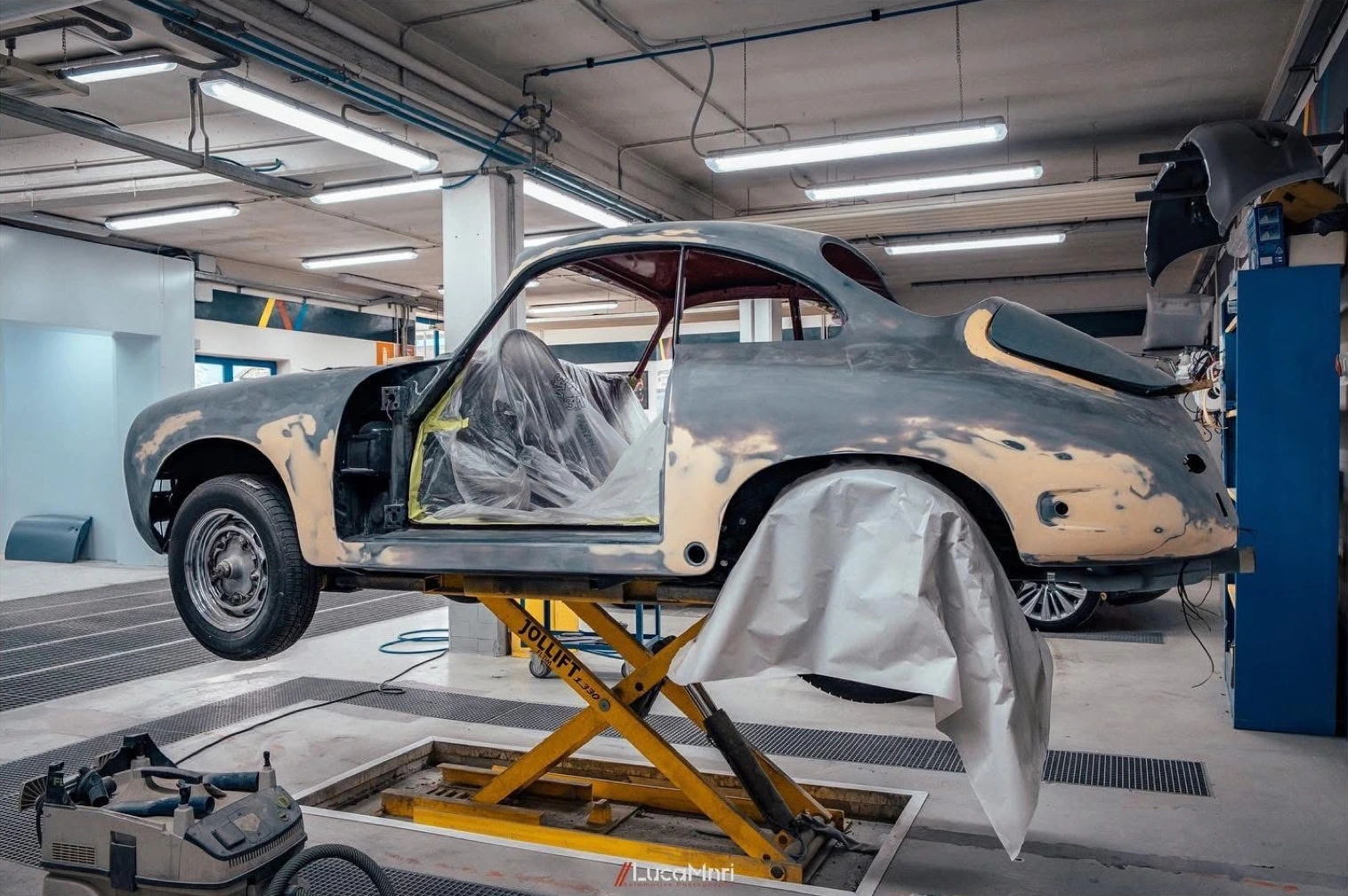 Scocca completa di una Porsche 356 in restauro, sollevata sul ponte in officina